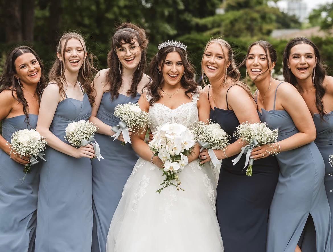 Bride in a tiara laughing with her bridesmaids in dusty blue and navy, garden wedding